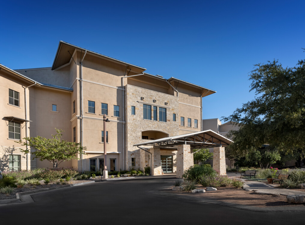 view of the beautifully landscaped exterior entrance of the Health Services building at Querencia Senior Living Community in Austin, TX